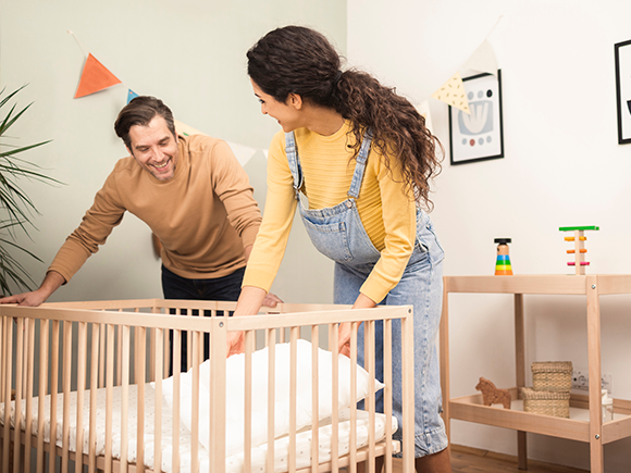 Un hombre y una mujer preparan la cuna del bebe