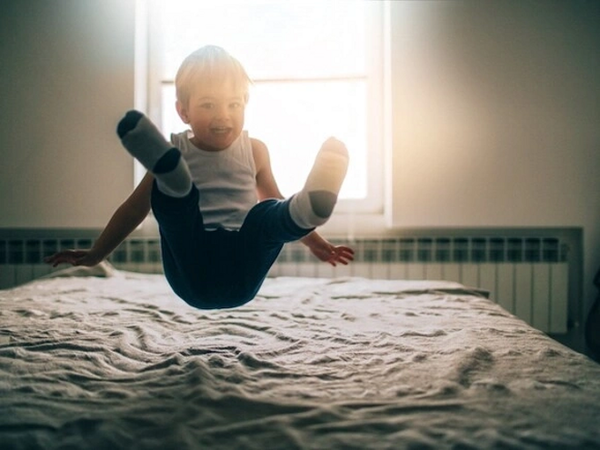 niño saltando sobre la cama